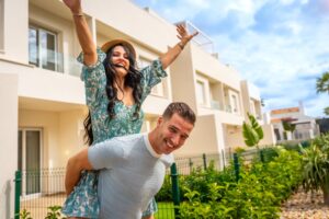 Happy newlywed couple piggybacking celebrating buying a house