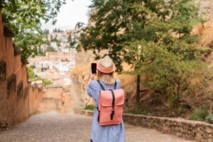 Young traveler woman taking a picture with her phone on the street in Granada. Travel concept