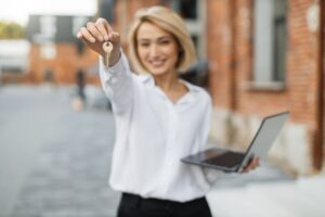 Real estate attractive agent beautiful woman with house keys in front of sold apartment.
