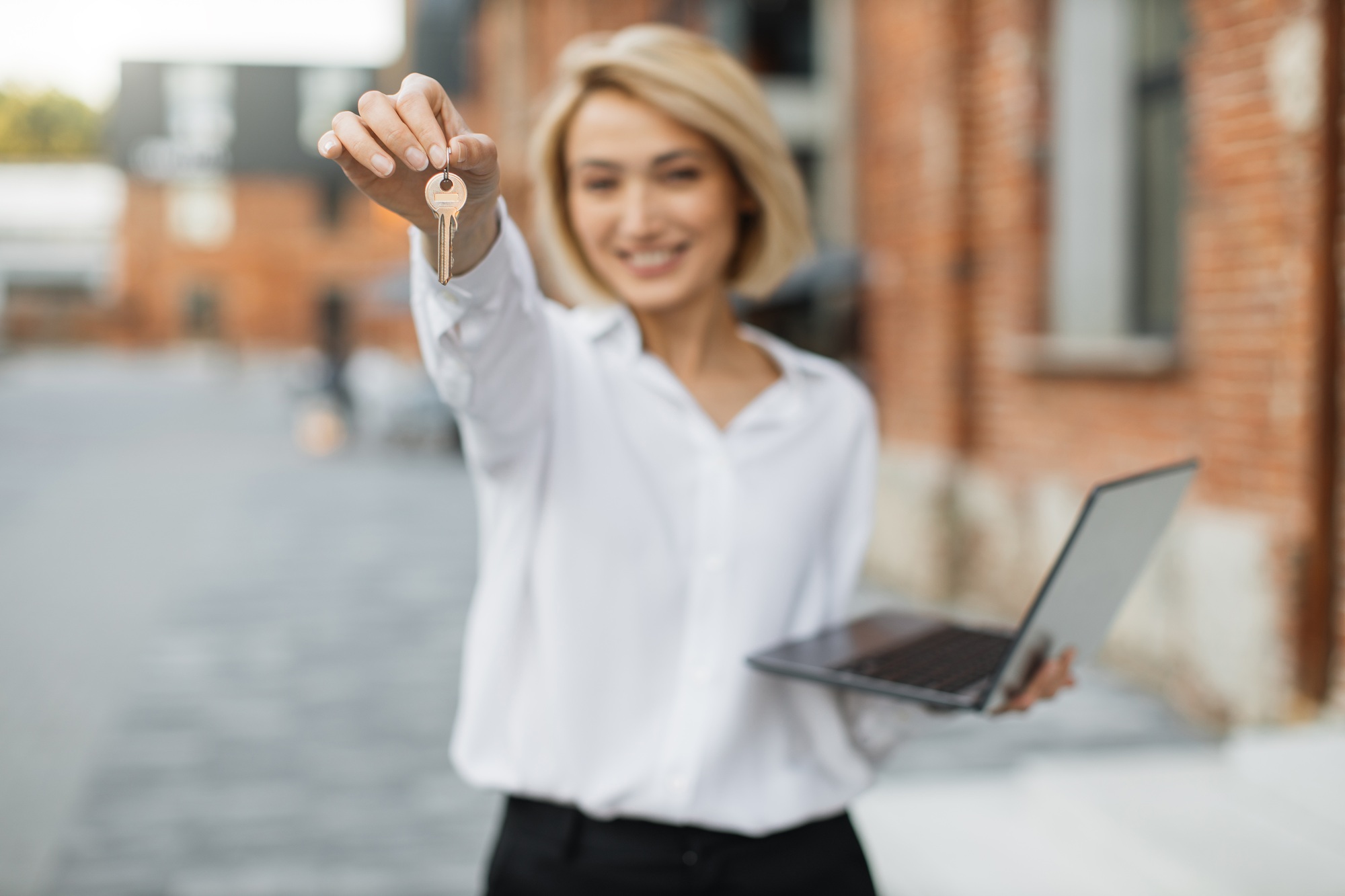 Real estate attractive agent beautiful woman with house keys in front of sold apartment.