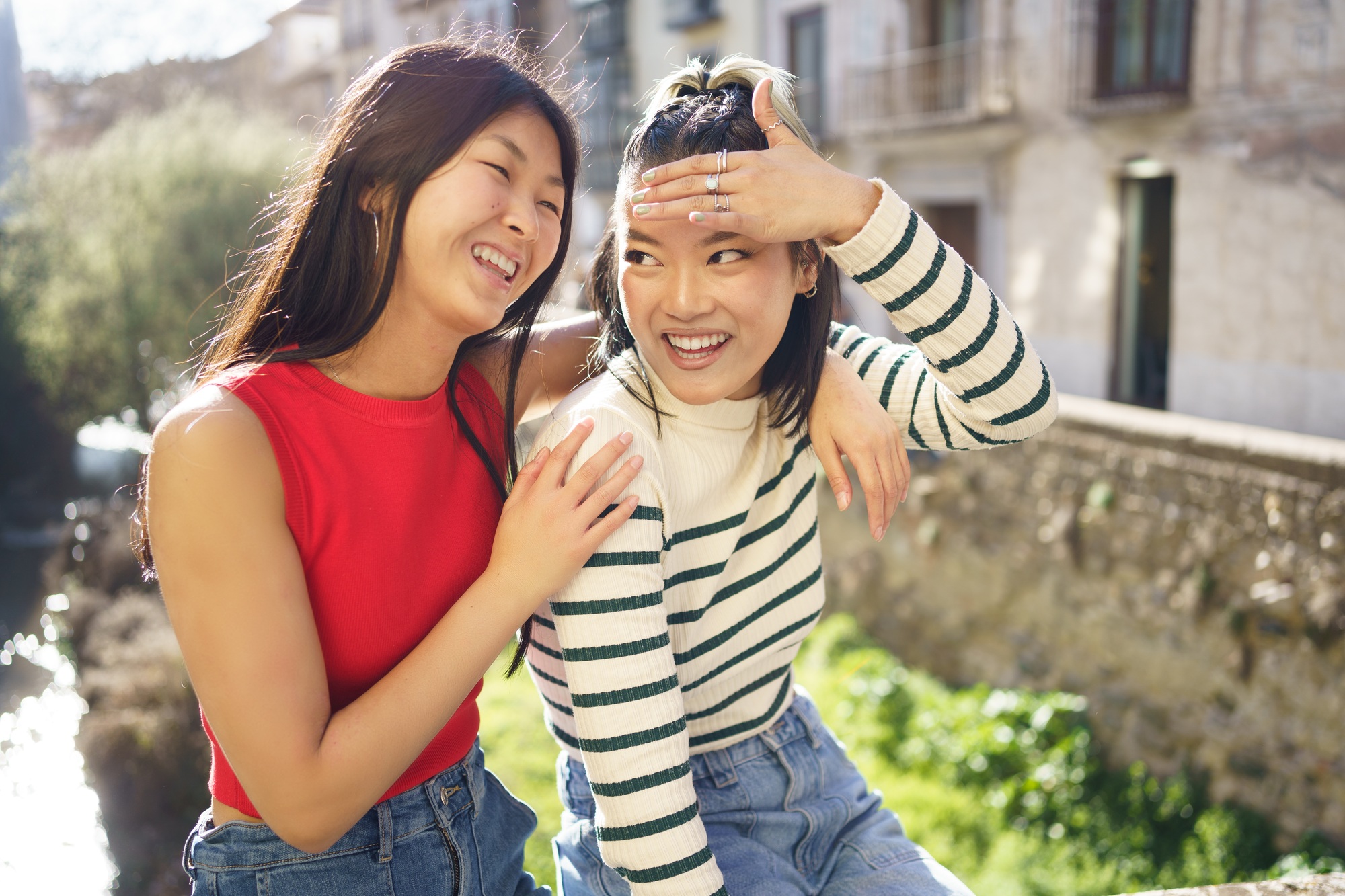 Cheerful Asian girlfriends having fun together in street
