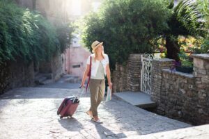 Girl traveler with suitcase at narrow italian street. Woman tourist is searching apartment, housing.