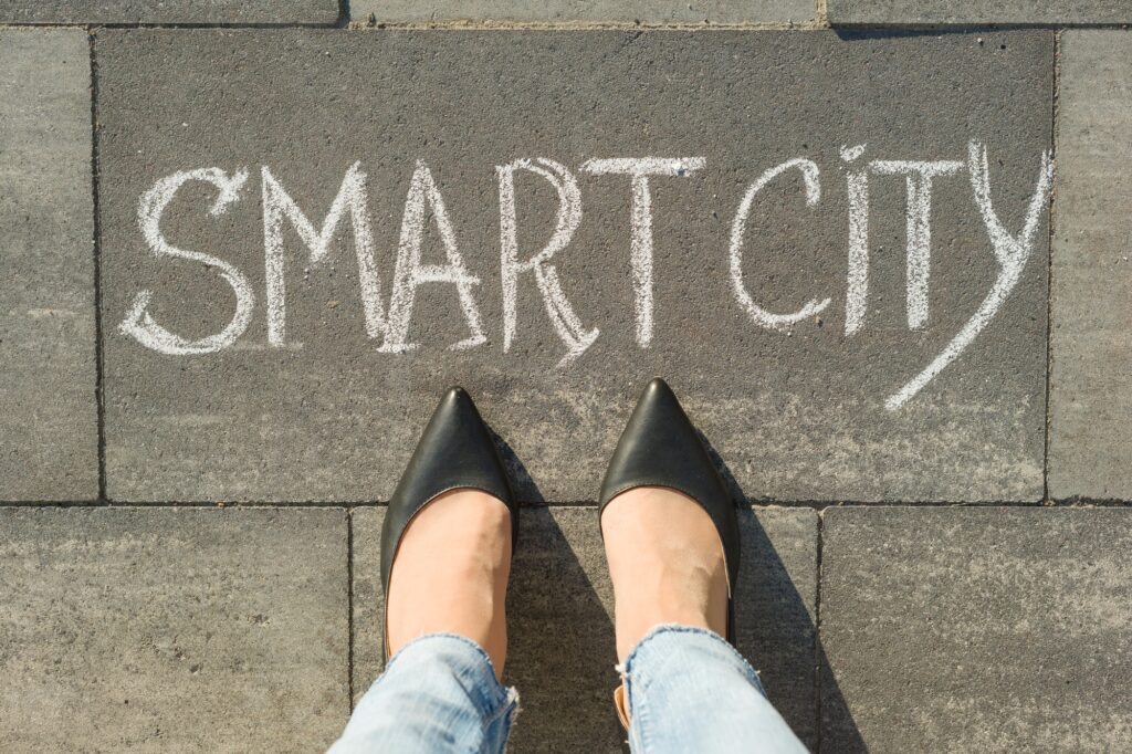 View from above, female feet with text smart city written on grey sidewalk.